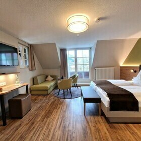 Zimmereinrichtung mit Doppelbett, TV und Sitzecke im Gstezimmer des Gasthaus goldener Engel